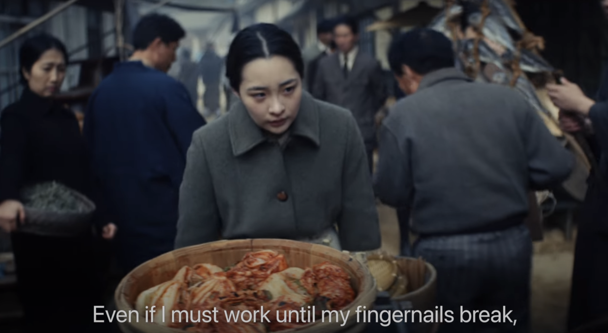 Sunja pushing cart in market with the caption &quot;Even if I must work until fingernails break&quot;
