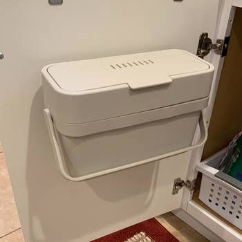 a reviewer photo of the compost bin mounted on the back of a cabinet door