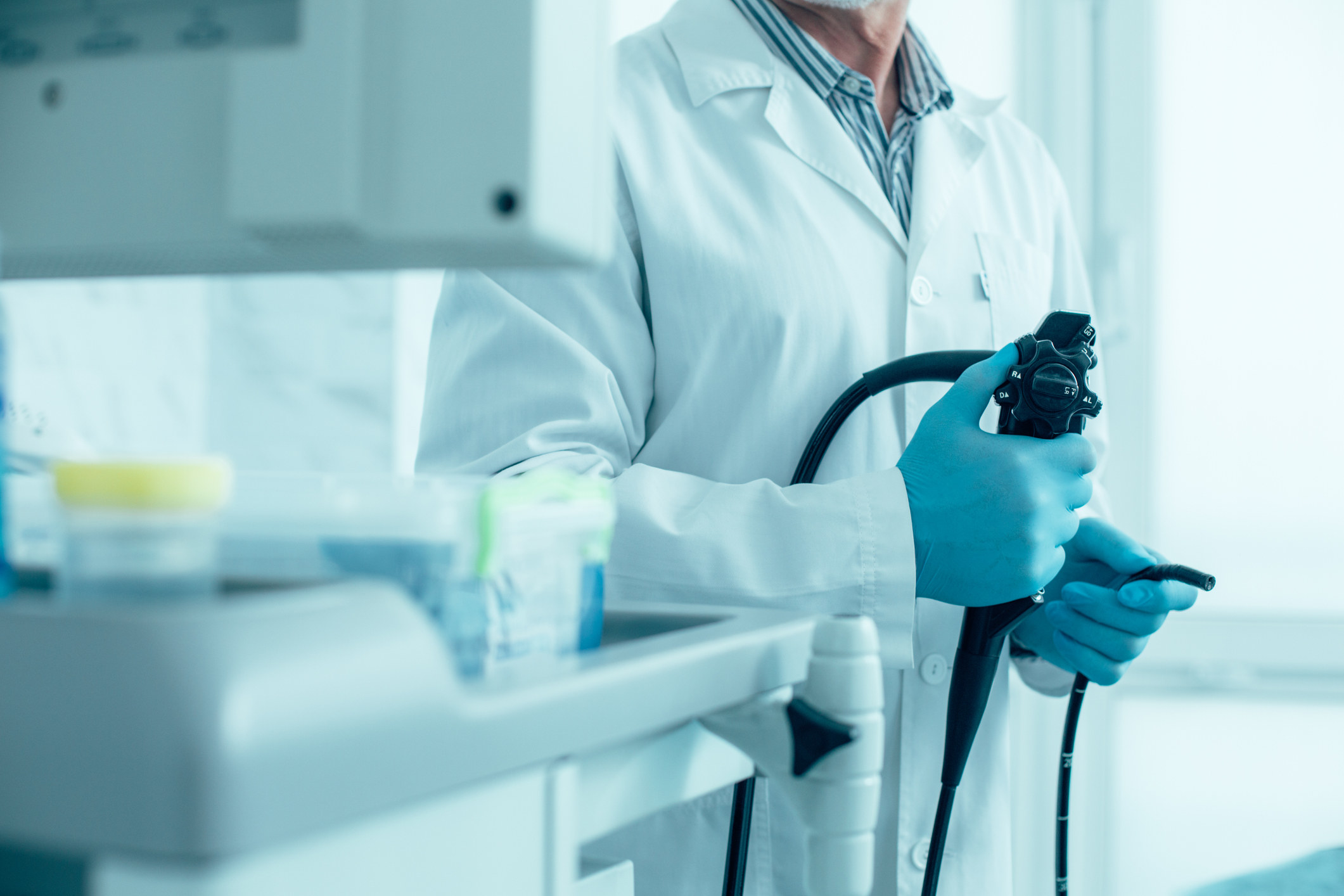 A doctor holds a large instrument with gloves, ready to perform on a patient