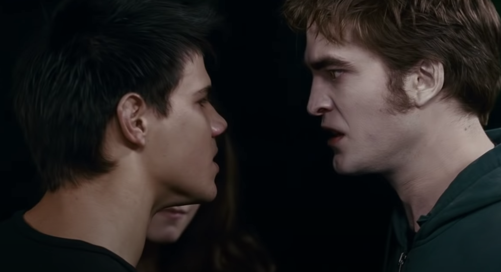 Two characters facing each other intensely in a movie scene, conveying tension. One character has short dark hair, the other has tousled hair