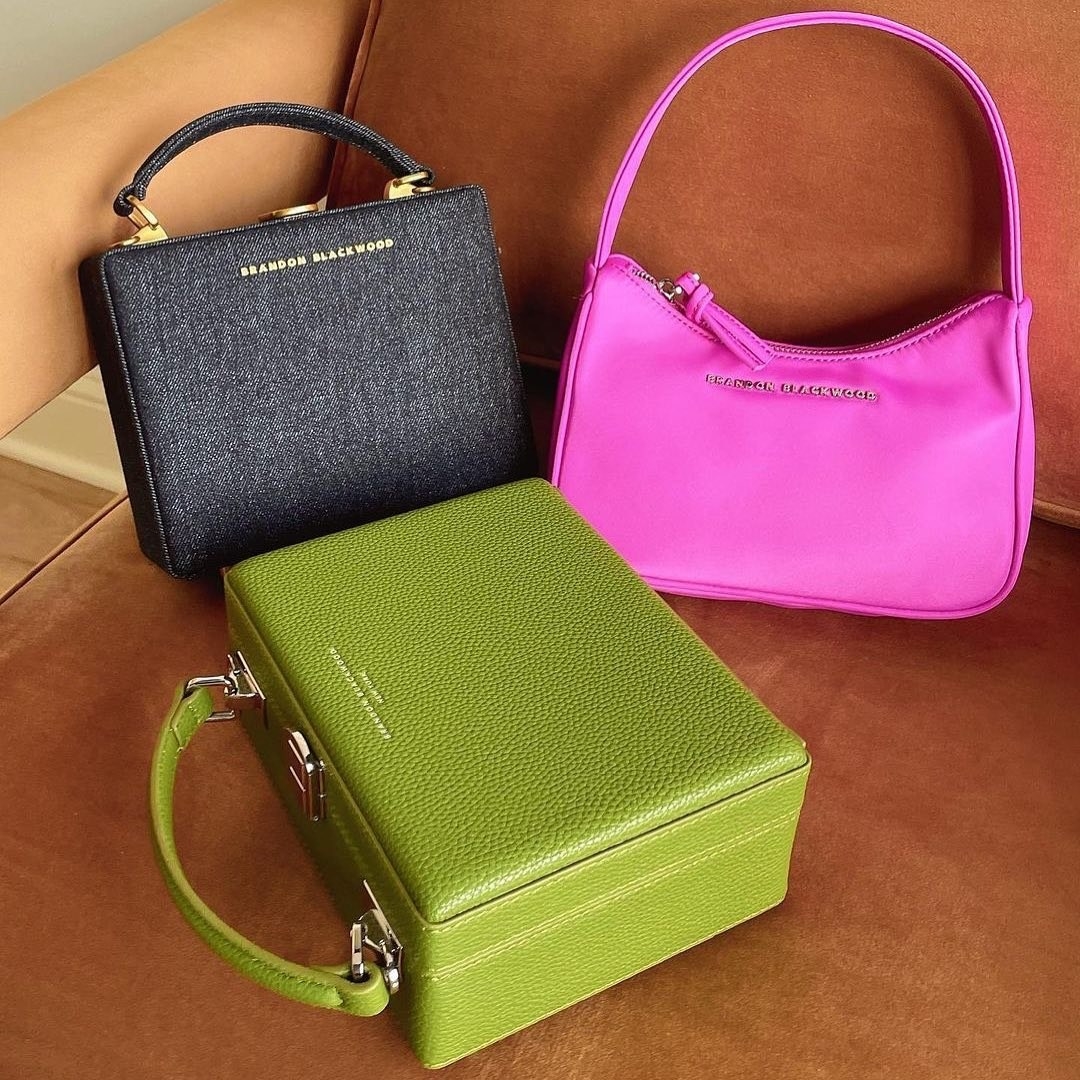 a green, black denim, and pink purse sitting on a chair