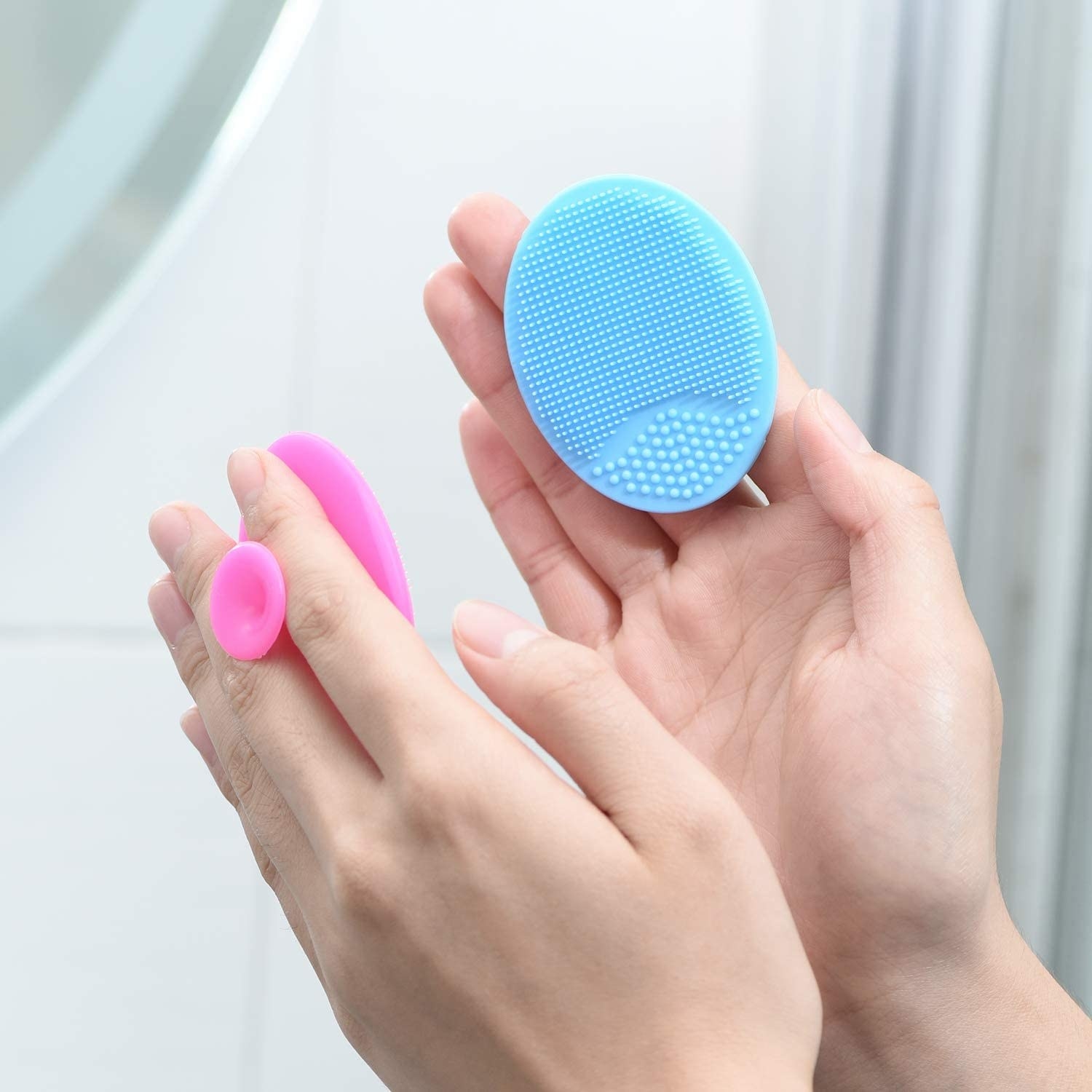 Someone holding two silicone scrubbers, one in each hand
