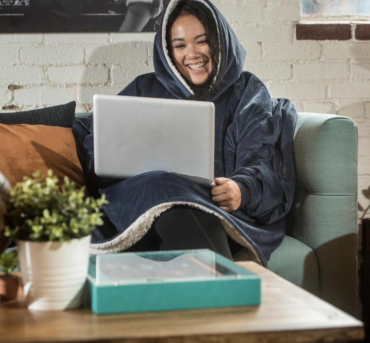 Model wearing the blue blanket while working on laptop