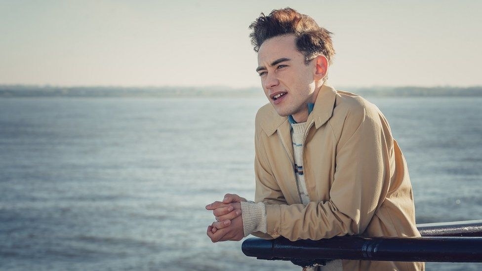 Olly Alexander as &quot;Ritchie&quot; in It&#x27;s a Sin is looking out with the sea as his background