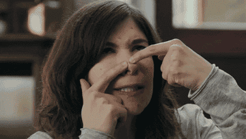 a gif of carrie brownstein from portlandia angrily popping a pimple on their face