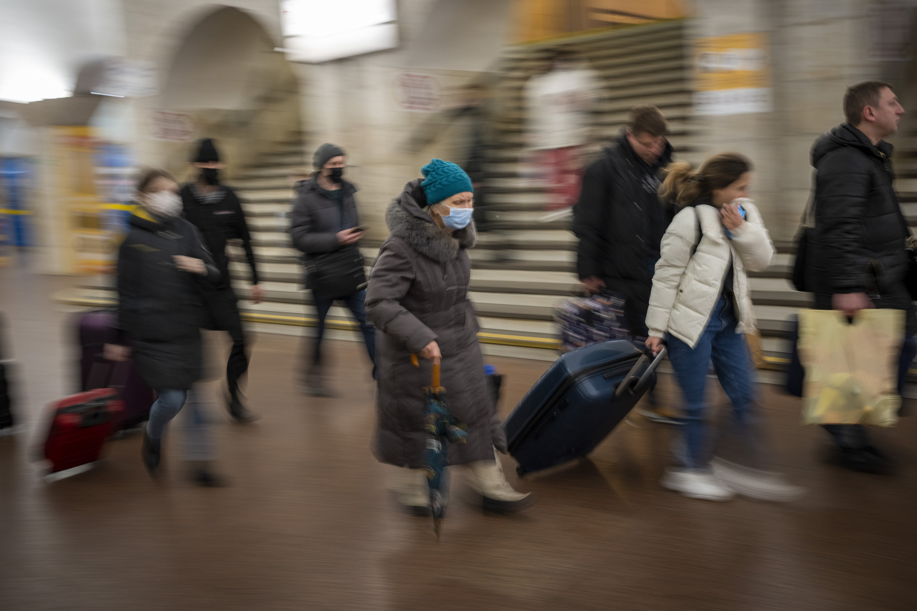 A blurry photo of people walking through the station with luggage
