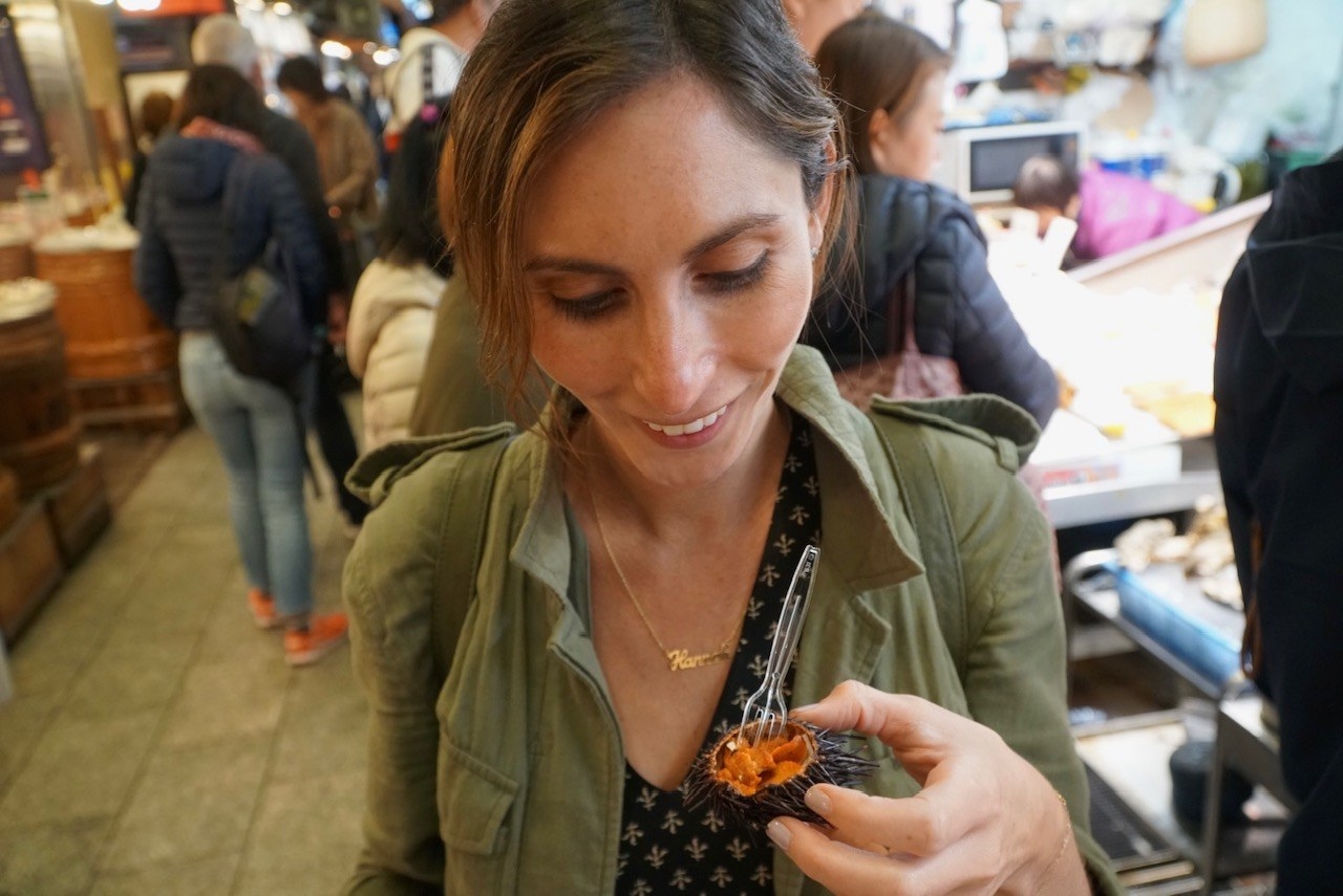 A woman at a food market holding a sea urchin