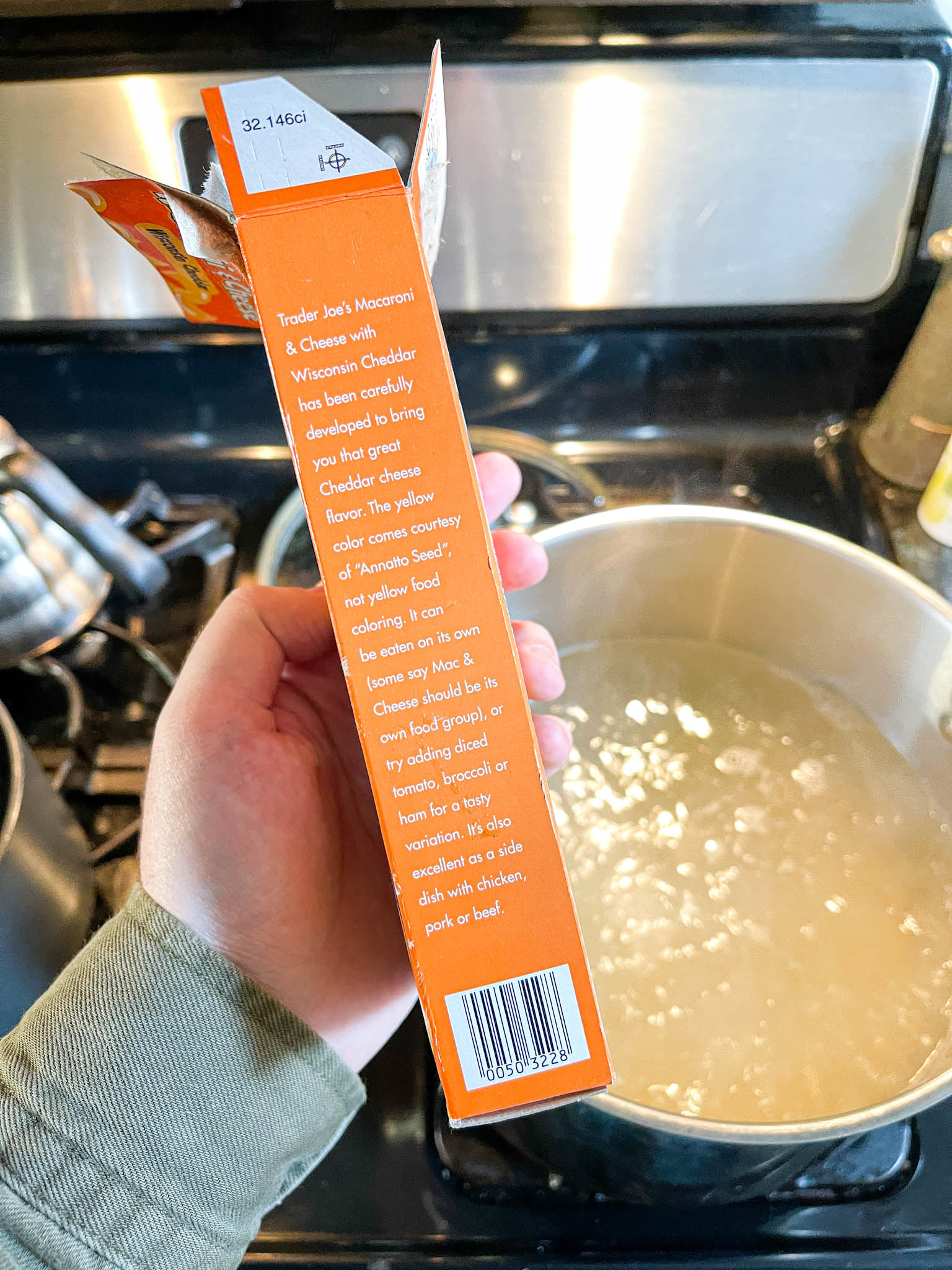 Author holding up the Trader Joe&#x27;s box in front of a large pot of boiling water