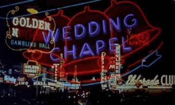 Neon blinking window signs that read &quot;wedding chapel&quot; and &quot;Gambling Little Casino&quot; lighting up