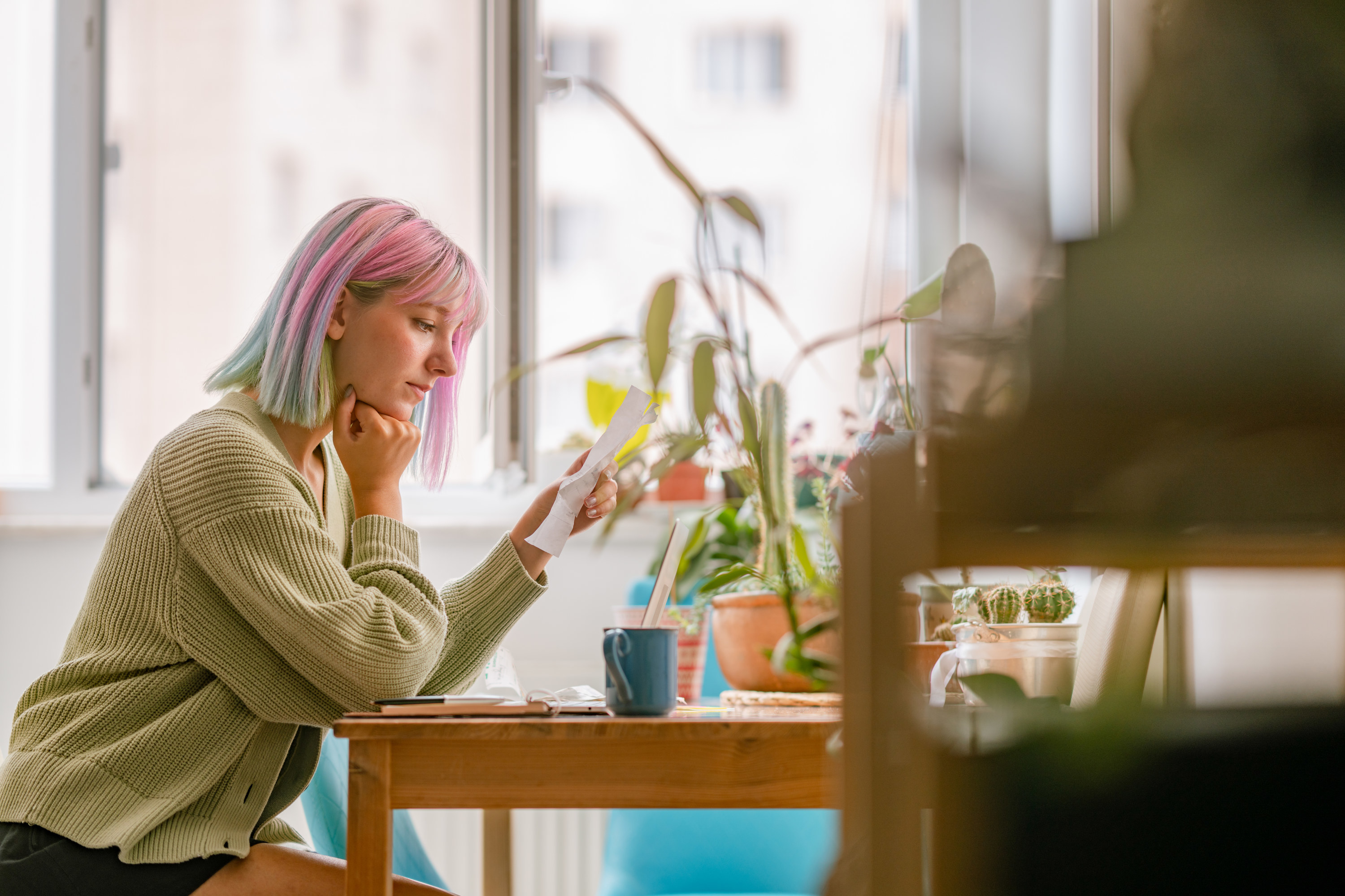 Young woman looking pensive at her kitchen table