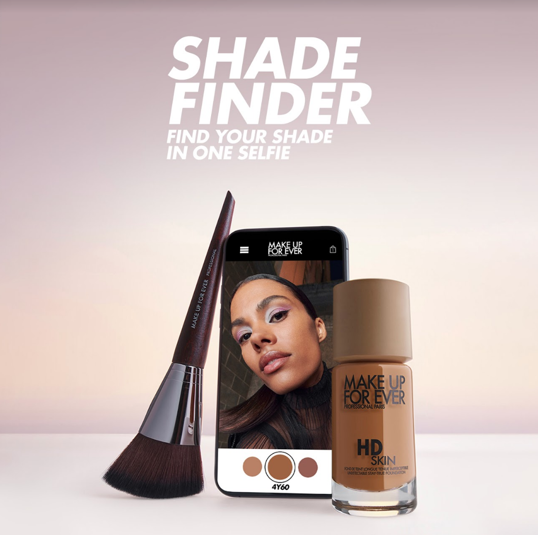 Shade finder website pulled up on a smartphone with a makeup brush and a bottle of HD skin leaning against it