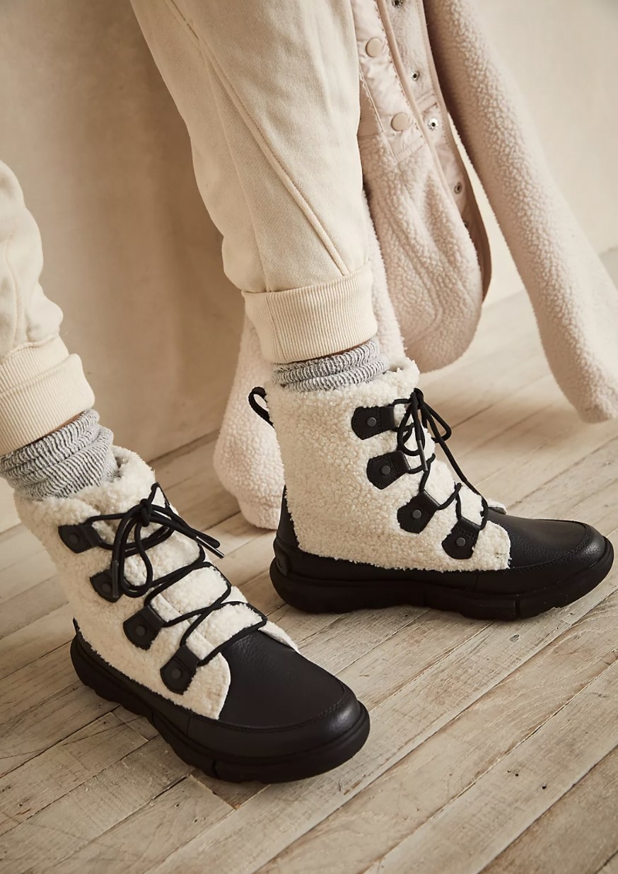 The boots with black outsoles and laces and white faux shearling upper