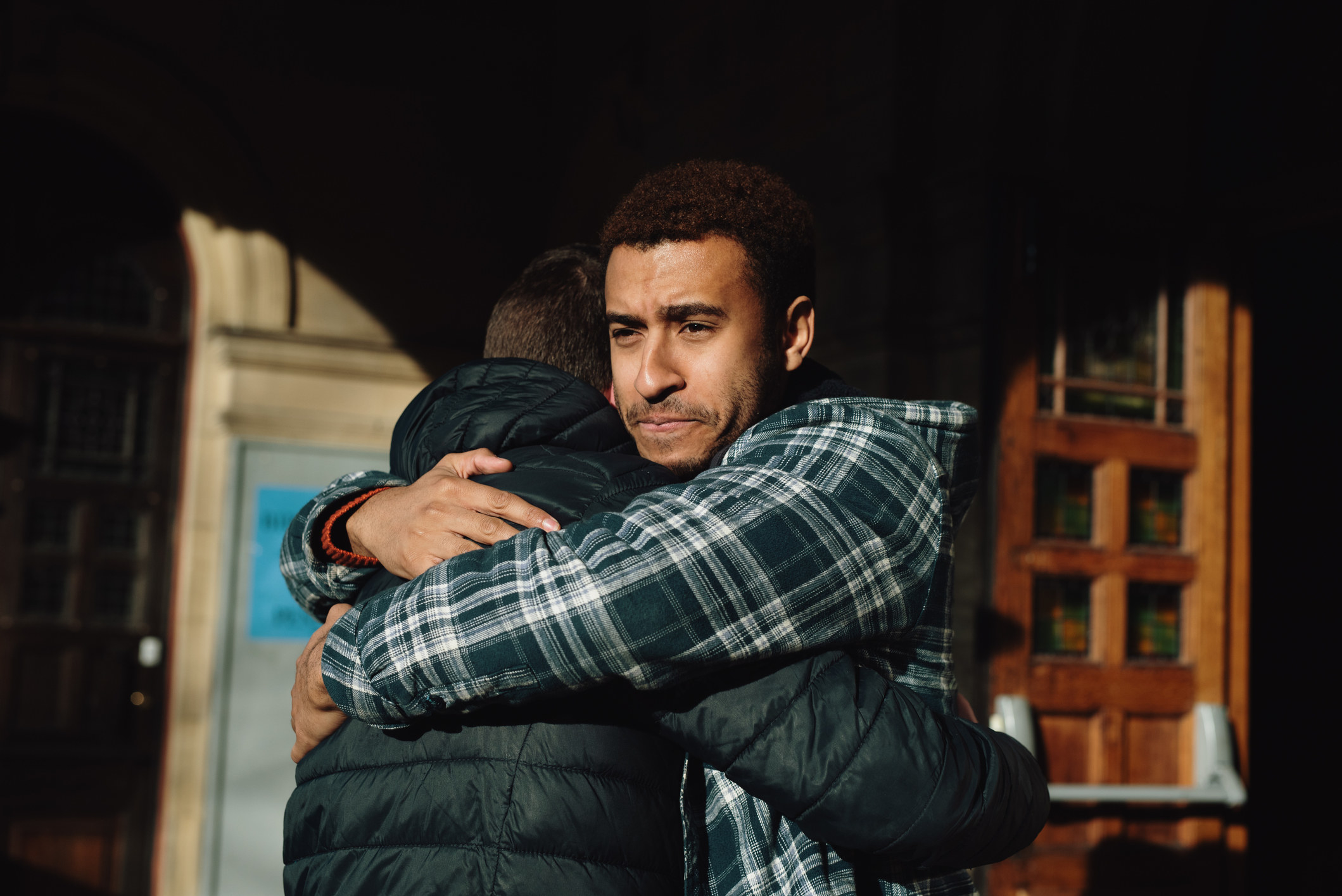 Man hugs someone while looking serious