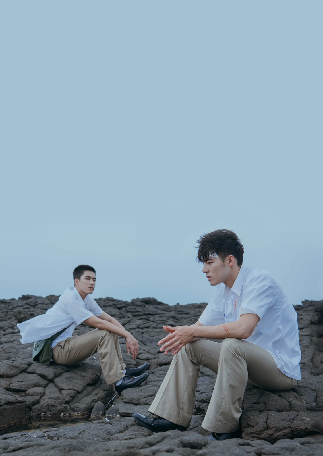 Tseng Ching-hua as Birdy and Edward Chen as Chang Jia-han sit on rocks by the beach in &quot;Your Name Engraved Herein&quot;