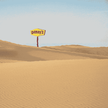 A Denny&#x27;s diner sign in the distance of a wide open desert scene