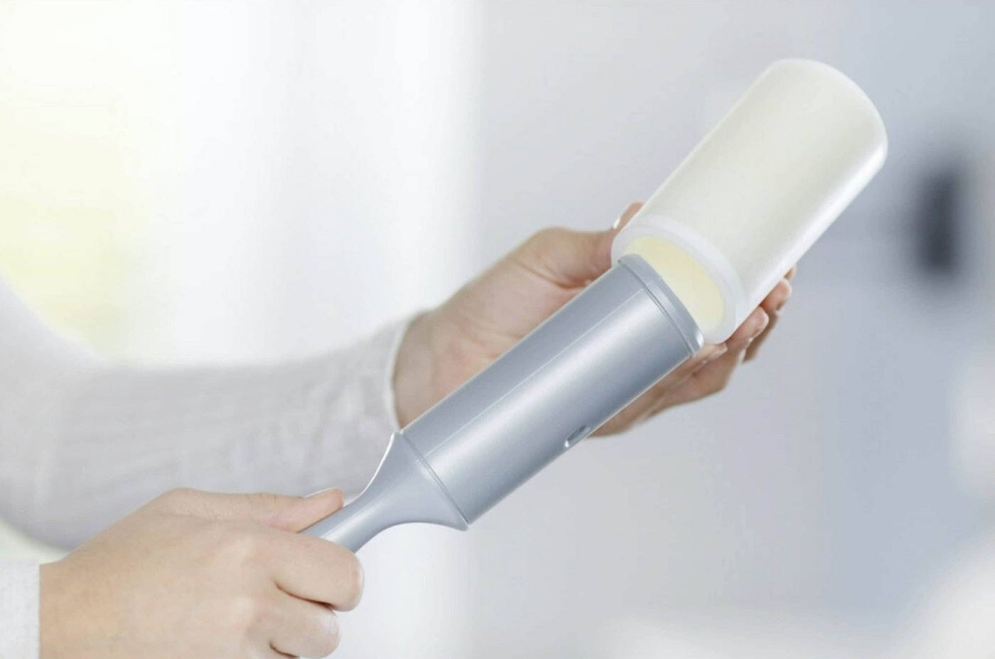 a person holding and refilling the lint roller