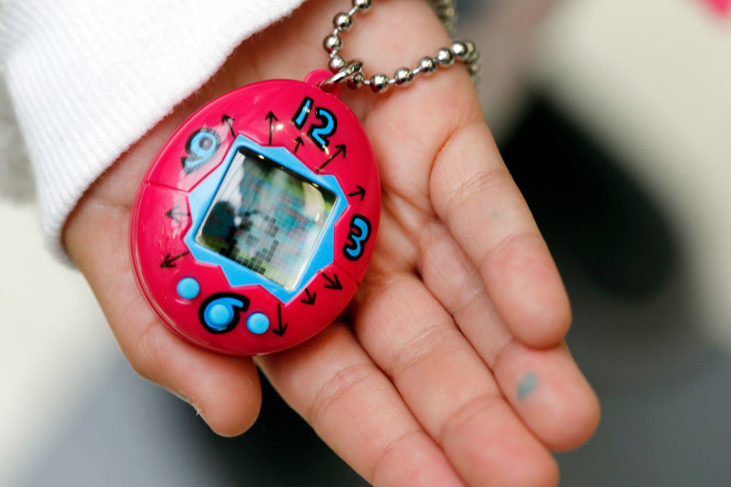 Kids hand holding a hot pink Tamagotchi