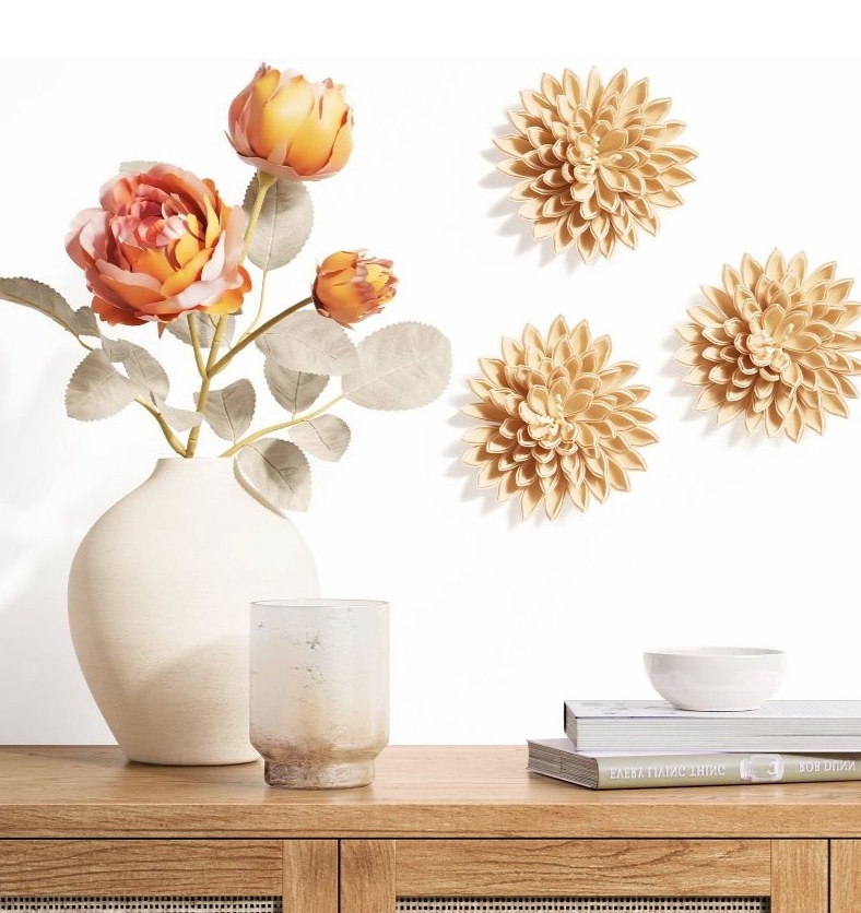 the three tan flowers on a white wall over a console table