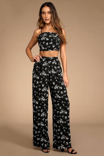 Model wearing the black and white floral printed strappy tie back top and high-waisted wide leg pants