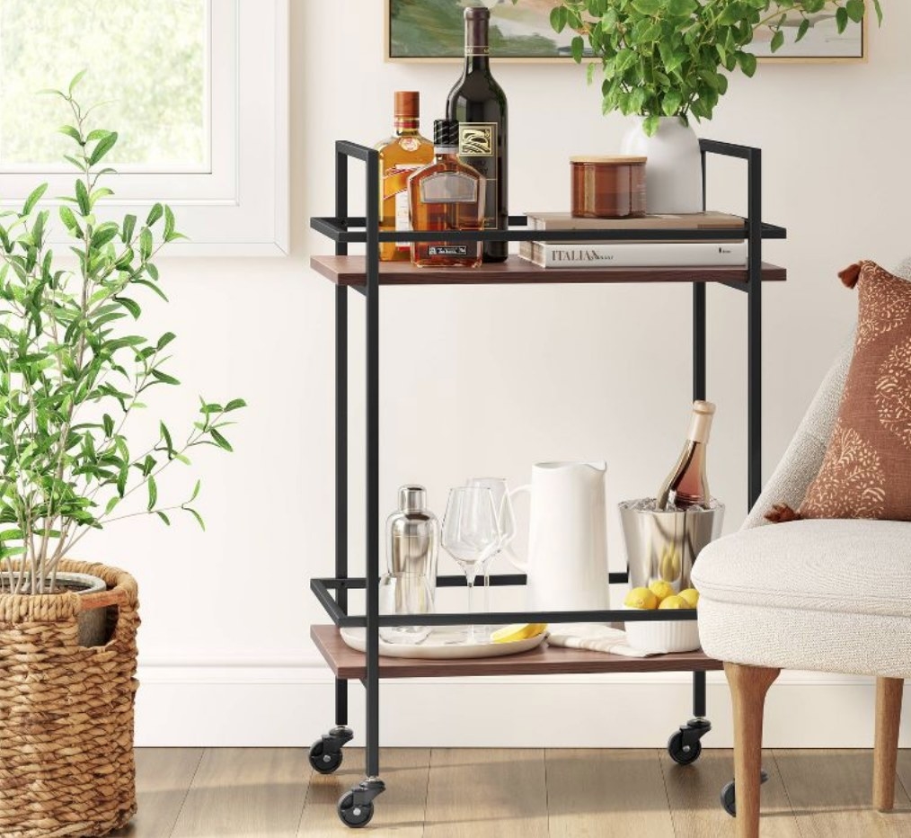 the wood and metal bar cart with books and bottles on it
