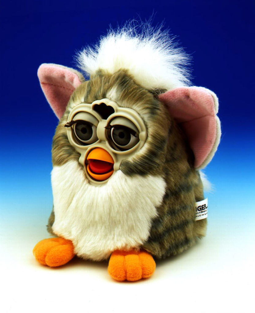 A white brown and black Furby against a blue backdrop