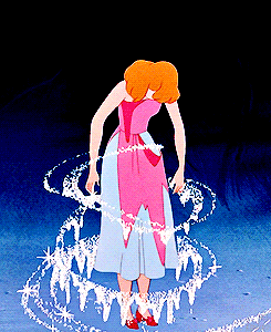 Cinderella stands as magic sparkles change her ratty dress into a ball gown