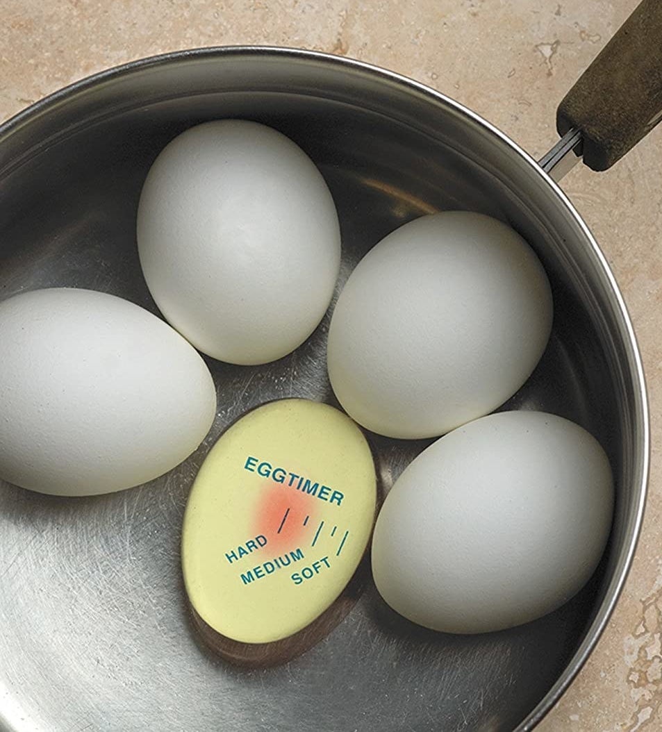 a colour-changing egg timer inserted into a pot of boiling eggs