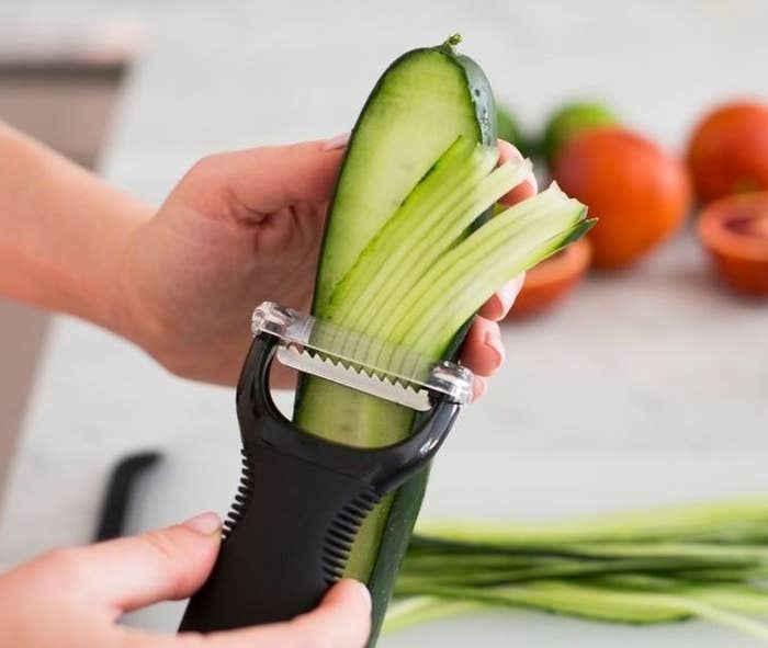 someone using the peeler to julienne a cucumber