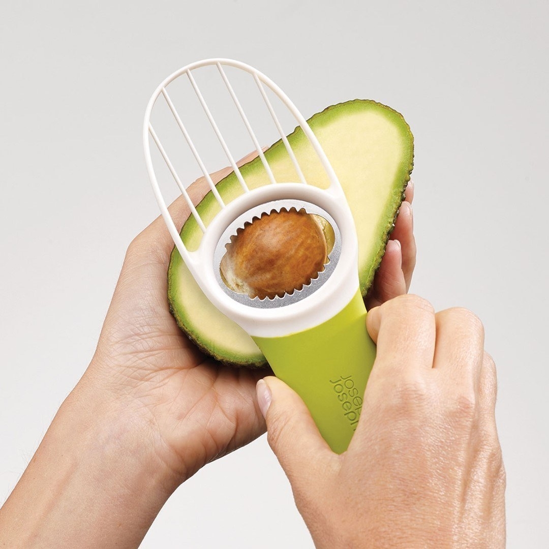 someone using the avocado tool to remove the inner pit