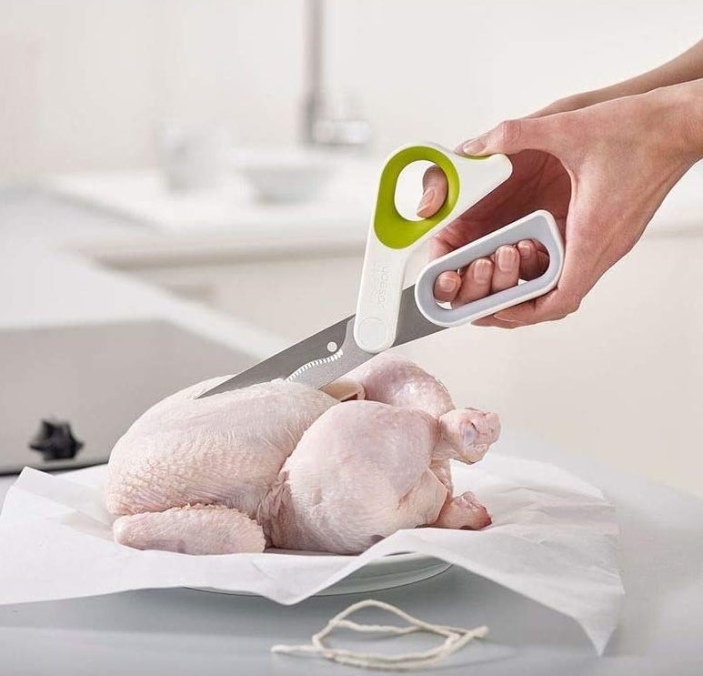 a person using the shears to cut through a whole chicken