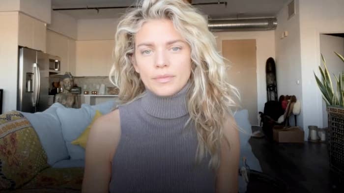 AnnaLynne McCord, a blonde white woman wearing a sleeveless turtleneck, faces the camera in her living room