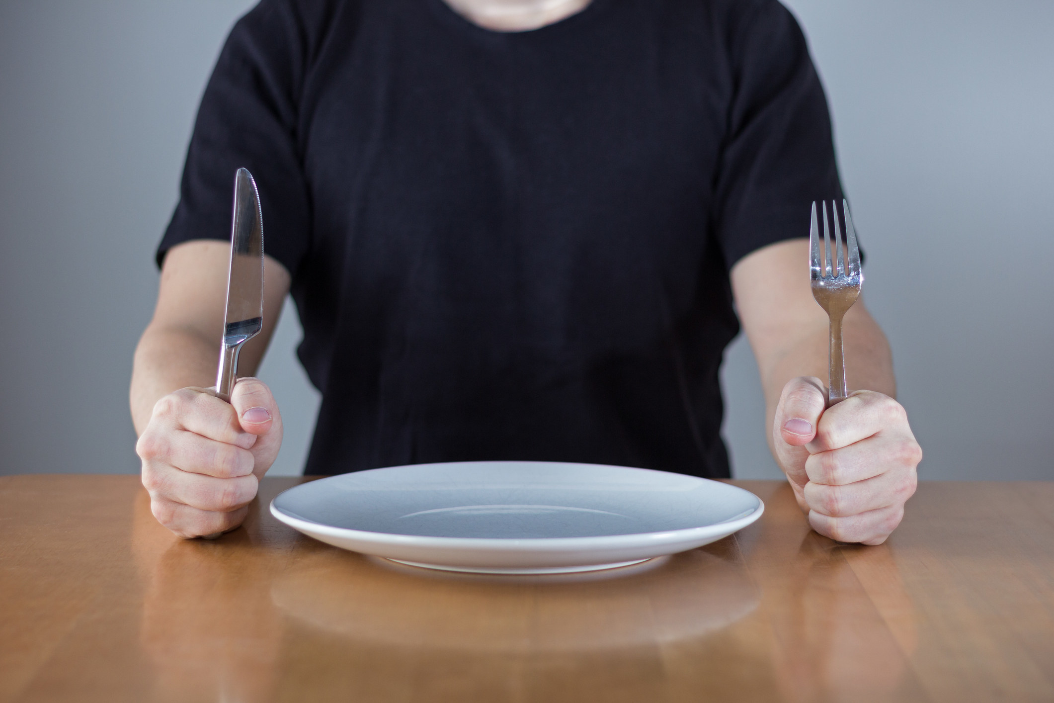 Someone holds a fork and knife, eagerly waiting dinner