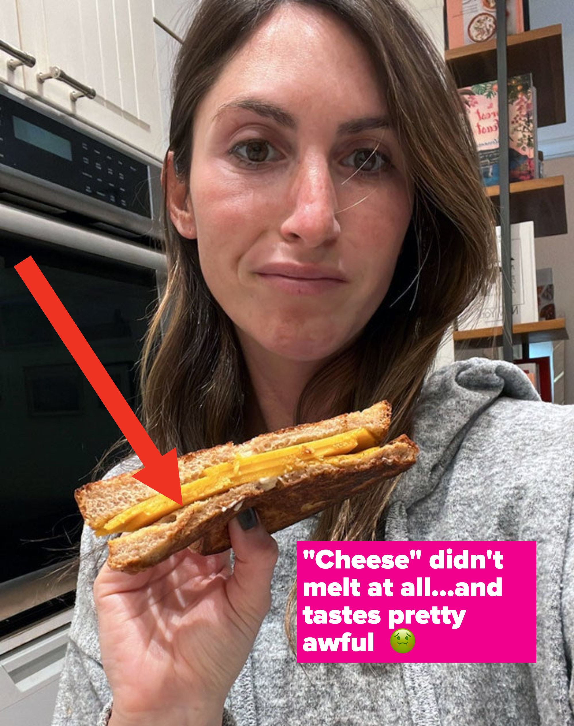 A woman holding a grilled cheese sandwich looking unhappy.