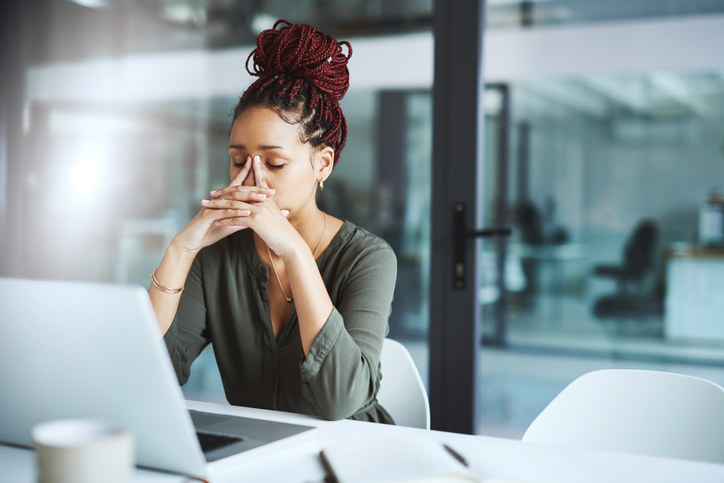 Black worker sitting in an office, looking frustrated