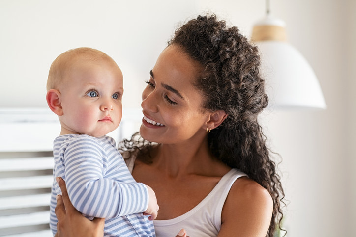 Black mother holding her white baby