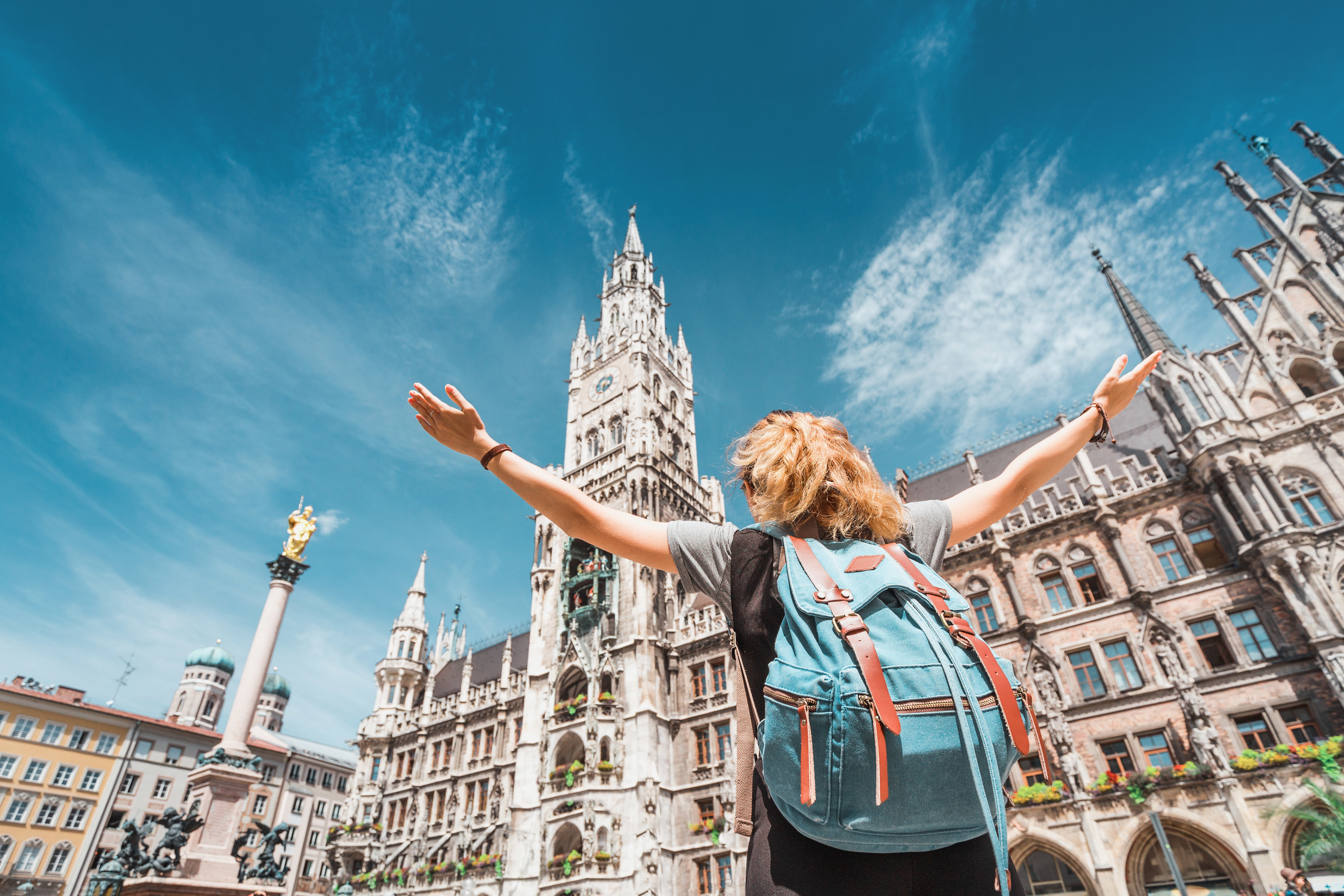 Woman raising her arms up in front of the university of Munich.