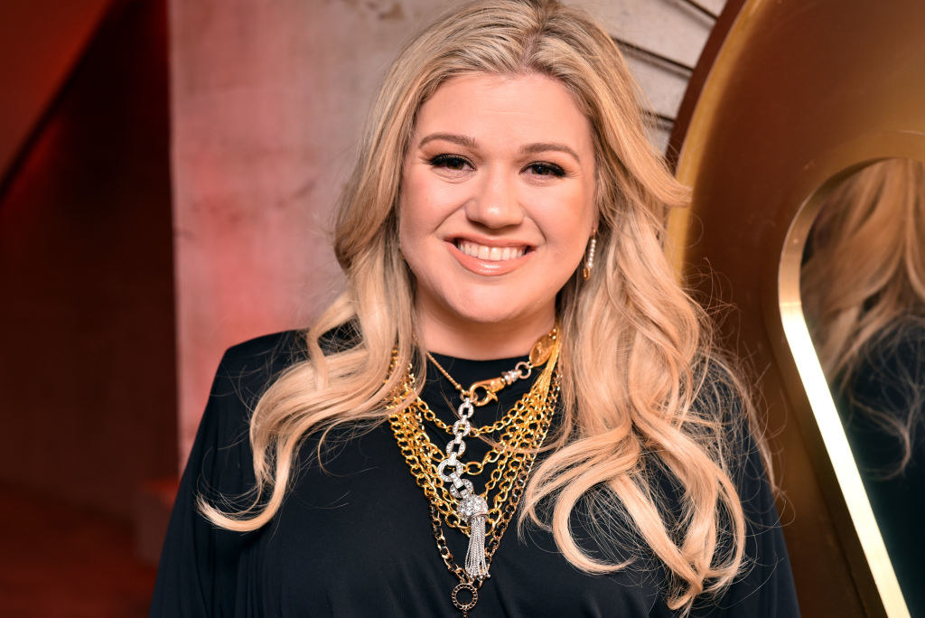 Kelly at a pre-Grammy event; her hair is blonde and she wears a blouse with layers of chain necklaces