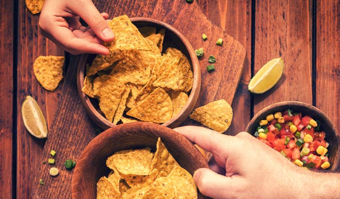 Close-up of hands reaching for chips on a table