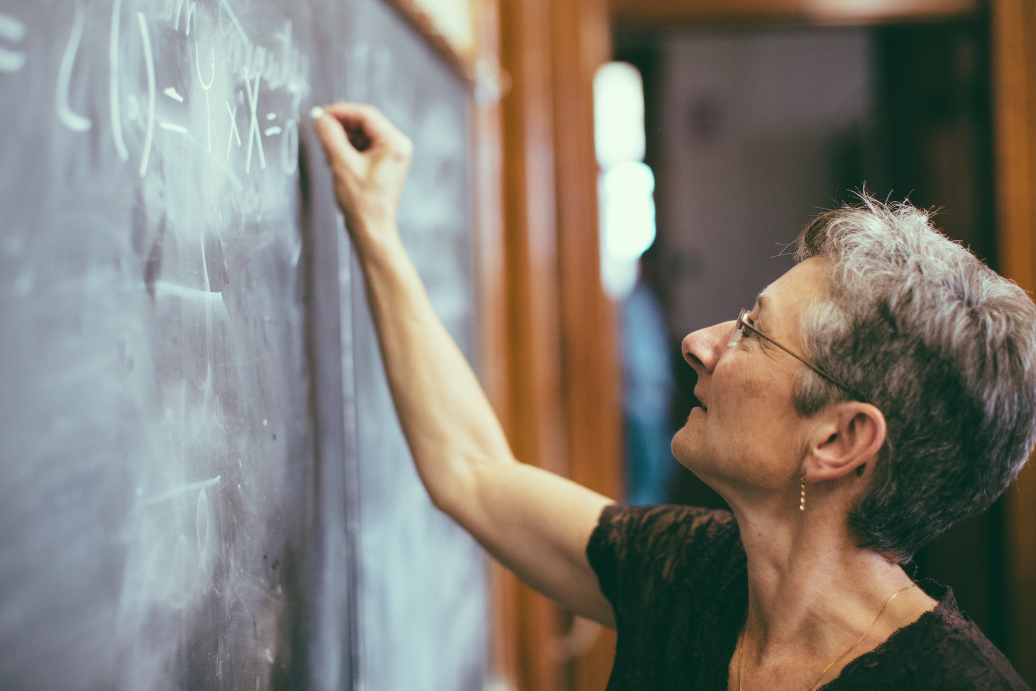 Teacher works on a math problem on the classroom chalkboard