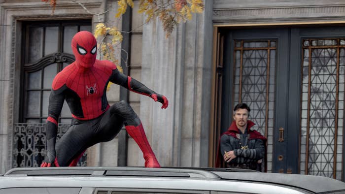 Spider-Man on top of a car while Dr. Strange watches from afar