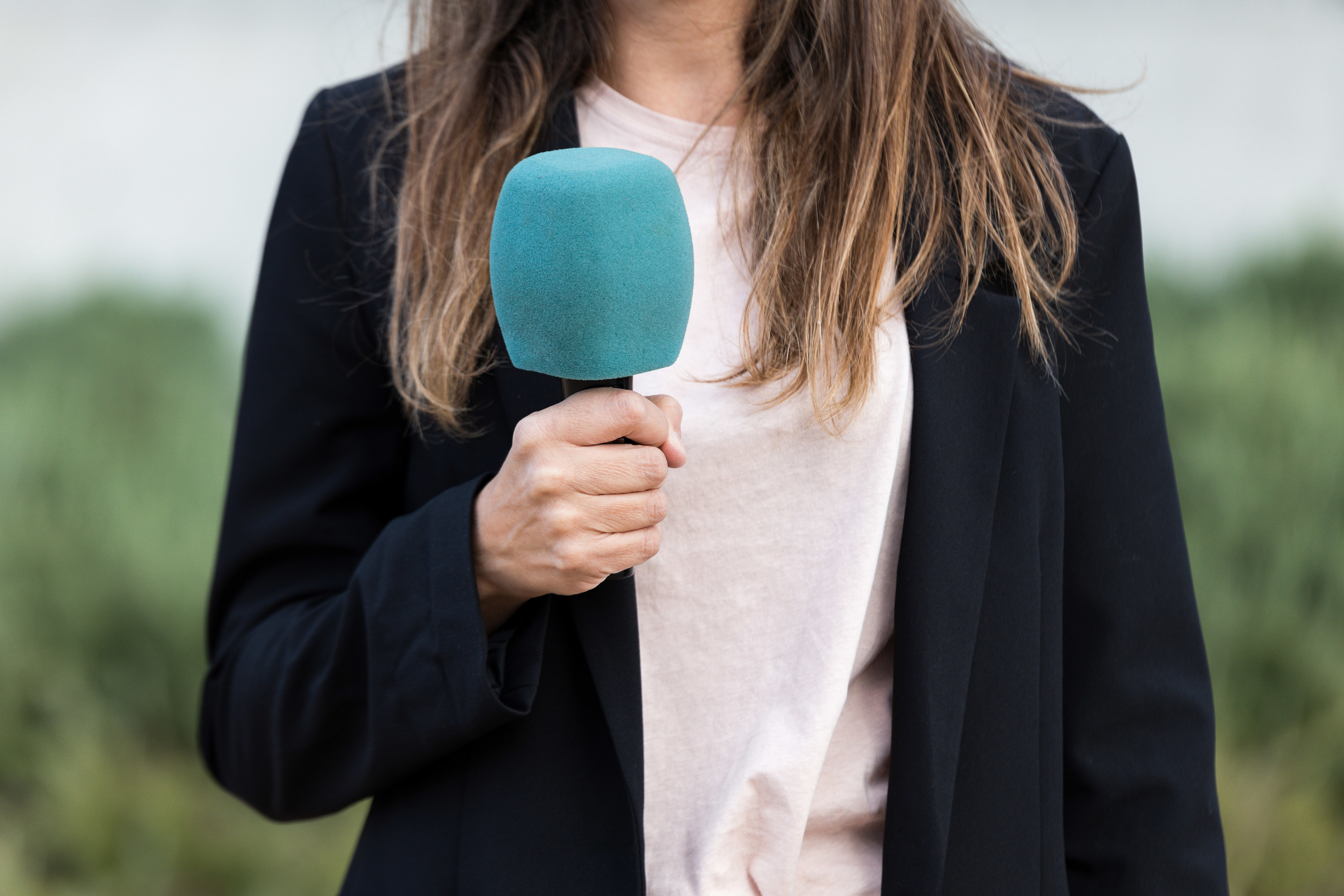 Close-up of a journalist holding a microphone ready to broadcast the news on the street