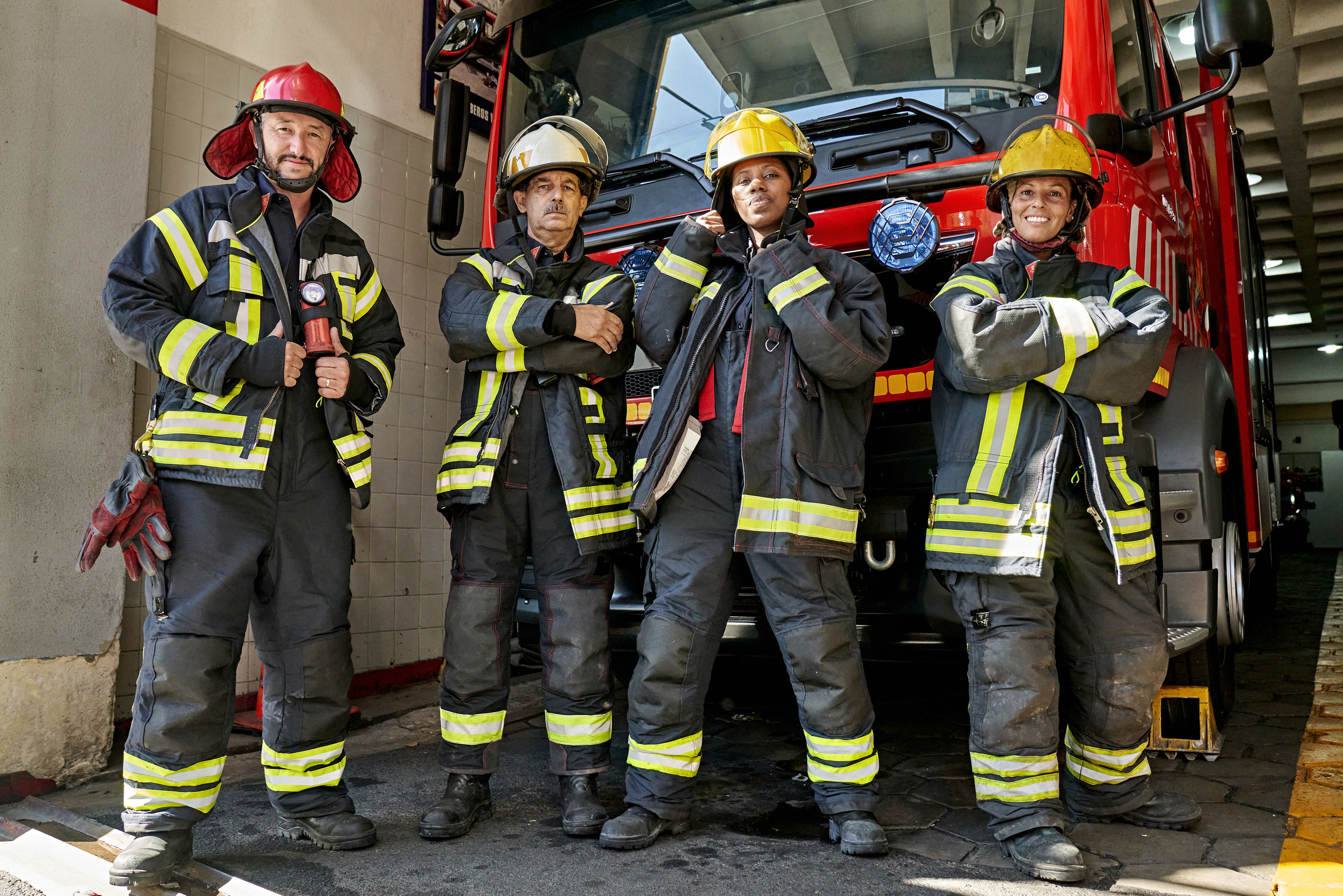 Four firefighters posing in front of a firetruck