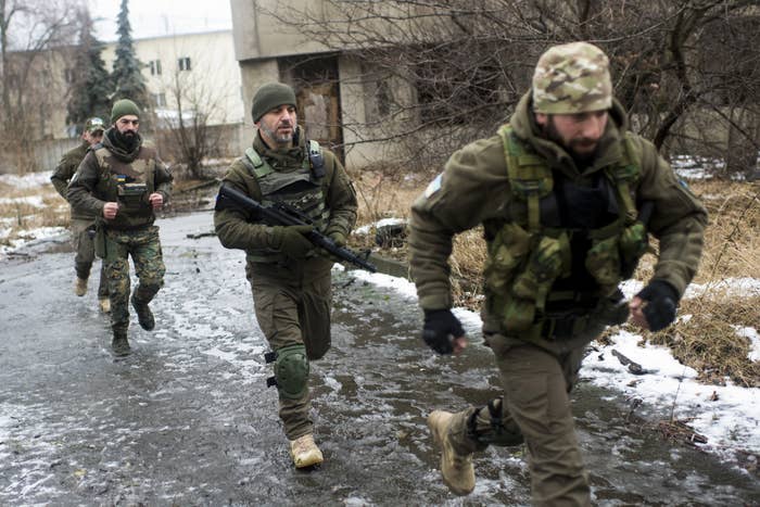 Four men in camouflage run down a slushy road