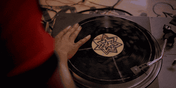 A hand scratching a record back and forth on a turntable