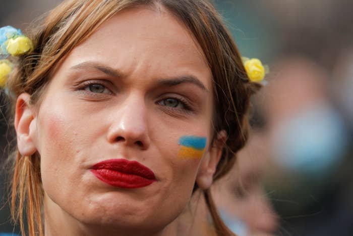 A person with blue and orange on her cheeks looks anguished