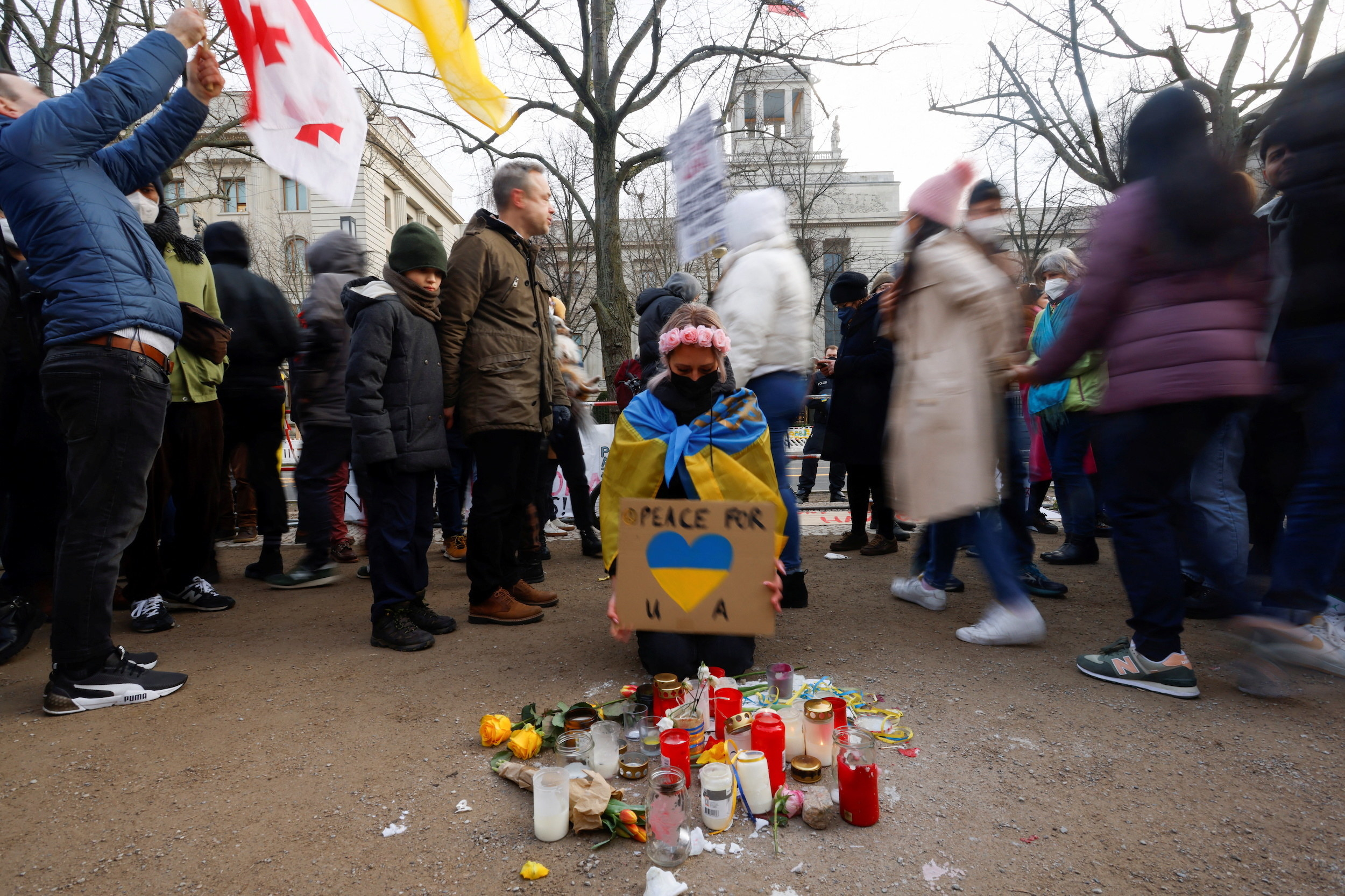 A group of people stand near a person with candles in front of them on the ground