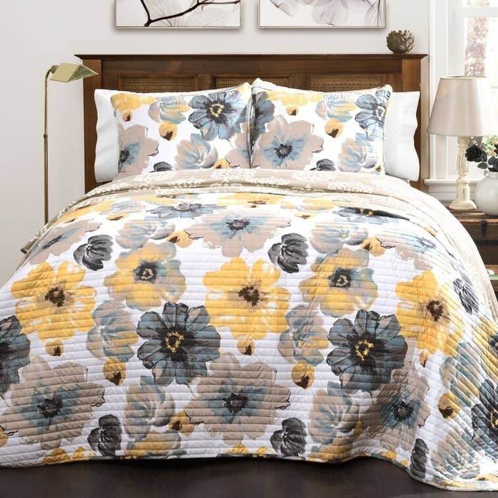 blue, gray, and yellow floral-print quilt with matching pillow shams on big bed
