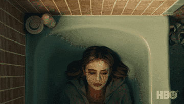 Cassie Howard lays in a bath tub with a face mask on as she cries
