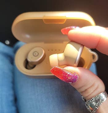 image of reviewer holding up earbud in front of charging case