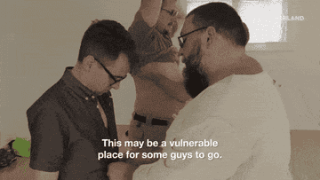 A man has his shirt unbuttoned and removed by another man